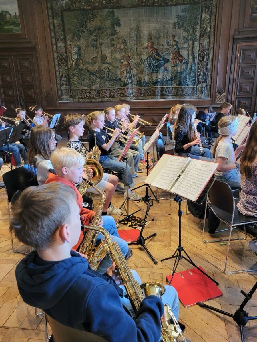 Die Orchesterklasse probt mit Saxophonen, Trompeten und Klarinetten in einem historischen Saal