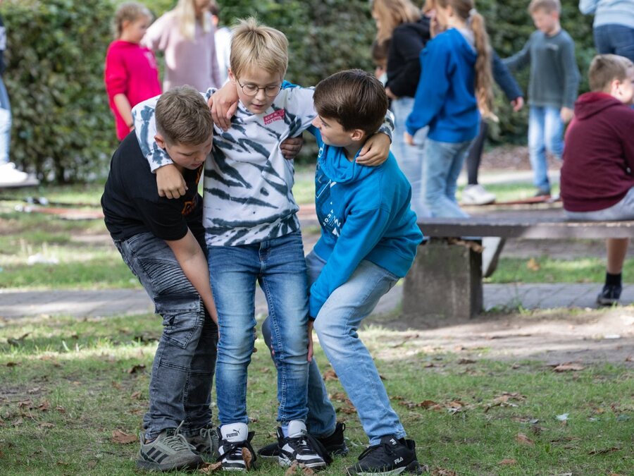 Drei Jungen halten sich in der Pause lachend gegenseitig fest