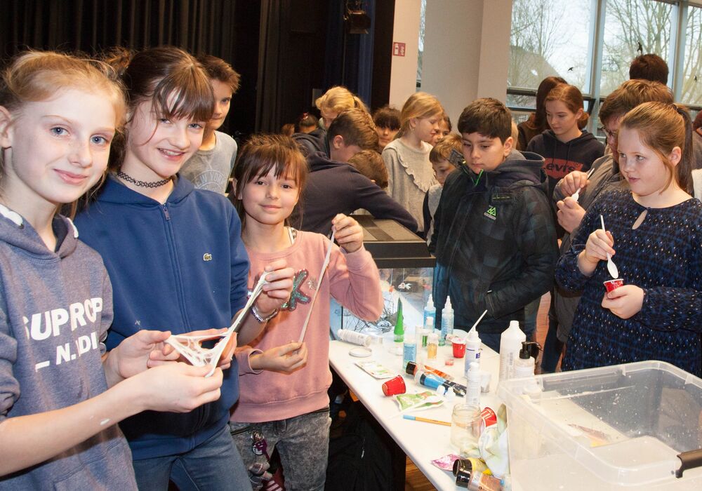 Kinder stellen bei einer Mitmach-Station selbst Schleim her